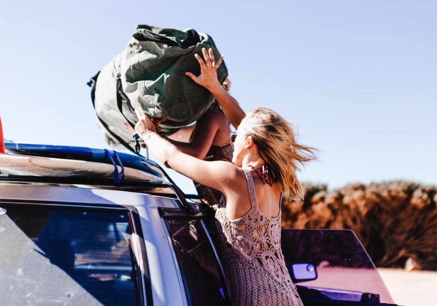 Voyageurs chargeant leurs sacs sur la galerie d'un 4x4 de location