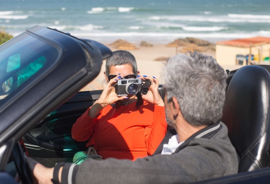 Couple en cabriolet de location photographiant le littoral